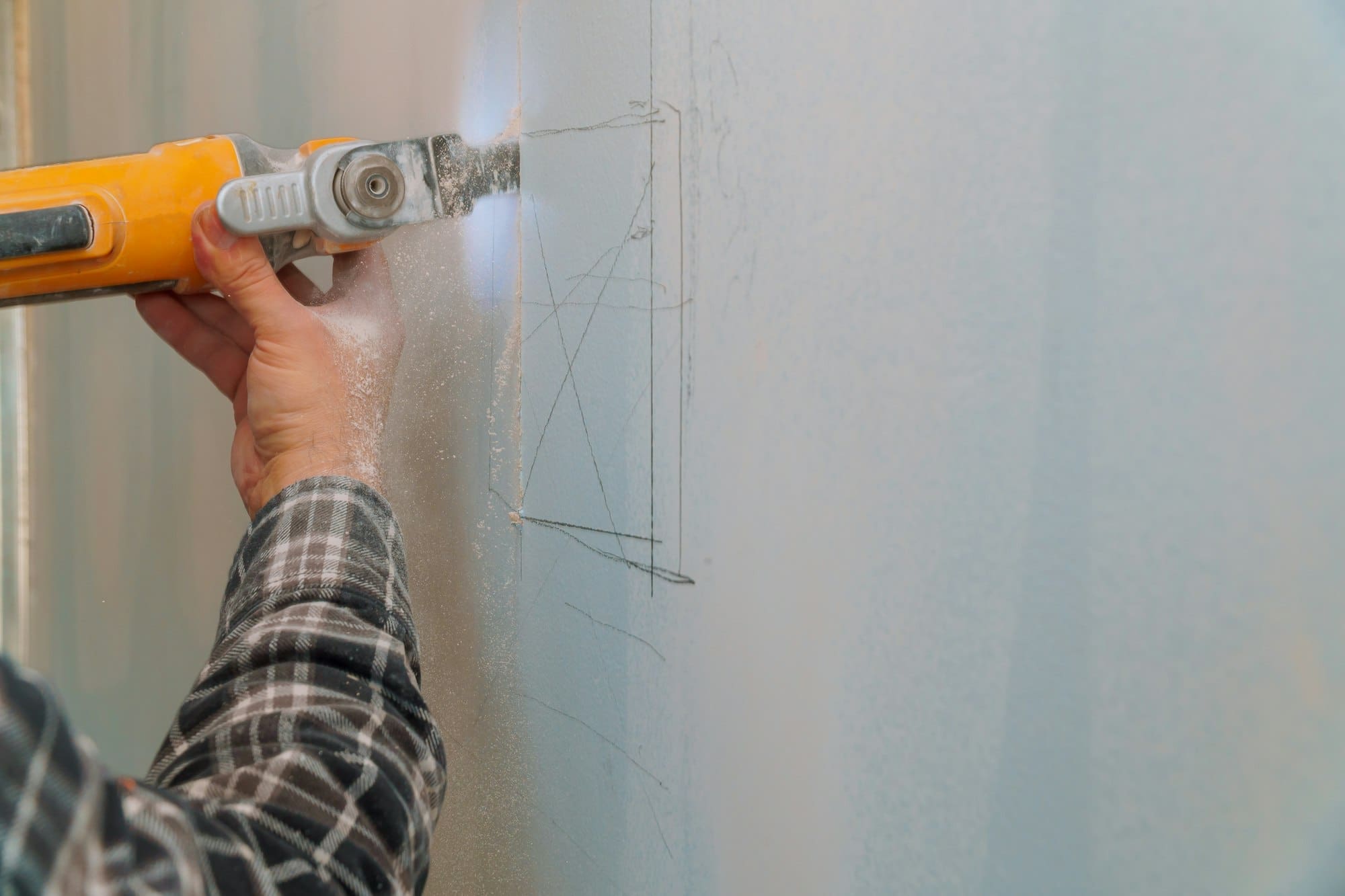 Construction worker cutting gypsum drywall by using electric cutter angle grinder
